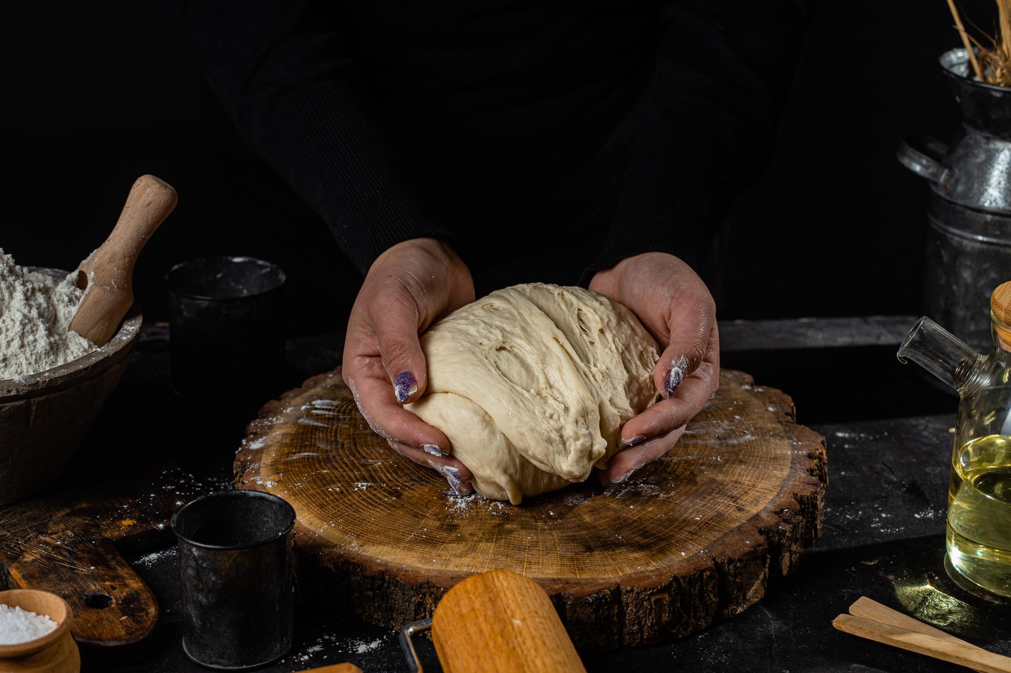 Chef stretching dough on wooden table